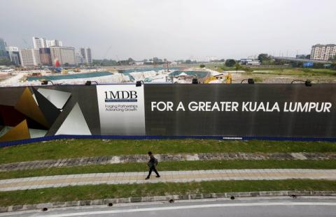 A man walks past a 1 Malaysia Development Berhad (1MDB) billboard at the funds flagship Tun Razak Exchange development in Kuala Lumpur, March 1, 2015. PHOTO BY REUTERS/Olivia Harris