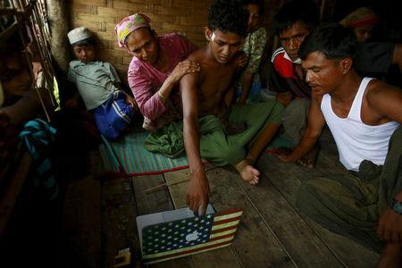 Abdhulami (C), 22, who was released from a human trafficking boat, points at pictures of people he recognises from the boat as he rests at a refugee camp outside Sittwe, Myanmar, May 27, 2015. PHOTO BY REUTERS/Soe Zeya Tun