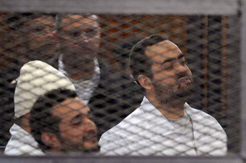 Political activists Ahmed Maher (in white hat), Ahmed Douma (L) and Mohamed Adel (R) of the 6 April movement look on from behind bars in Abdeen court in Cairo
