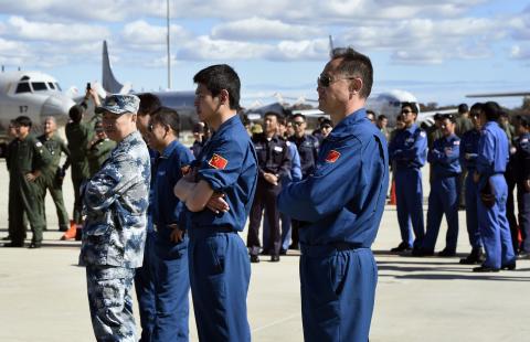 Air crew members from China, Malaysia and Japan involved in the search for missing Malaysia Airlines flight MH370, wait for an official photograph as they stand on the tarmac at the Royal Australian Air Force (RAAF) Pearce Base in Bullsbrook near Perth