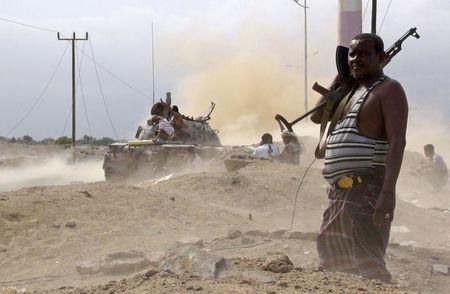 An anti-Houthi fighter of the Southern Popular Resistance stands guard as comrades fire from a tank in Yemen's southern port city of Aden, May 28, 2015. PHOTO BY REUTERS/Stringer