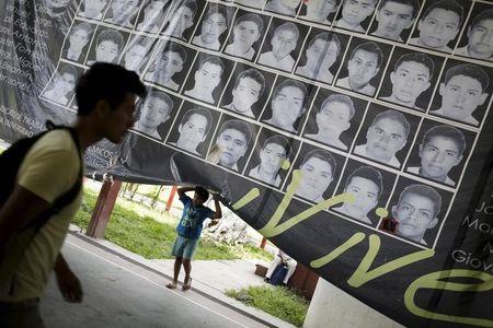 A child stands underneath a banner showing the photographs of the 43 missing students of the Ayotzinapa teachers' training college, at the college in Tixtla, on the outskirts oft Chilpancingo, in the Mexican state of Guerrero, August 15, 2015. PHOTO BY REUTERS/Jorge Dan Lopez