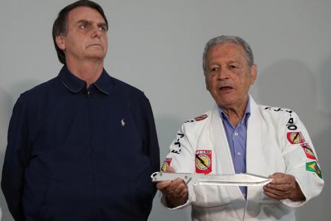Presidential candidate Jair Bolsonaro looks on as Robson Gracie, member of the Gracie Jiu-Jitsu family, holds a knife before gifting him with a jiu-jitsu black belt at a campaign office in Rio de Janeiro, Brazil, October 25, 2018. PHOTO BY REUTERS/Ricardo Moraes