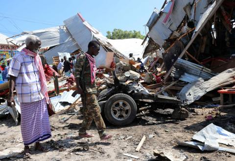 A Somali security officer walks past a trader as he secures the scene of an explosion at a market in Wadajir district in Mogadishu, Somalia, November 26, 2018. PHOTO BY REUTERS/Feisal Omar