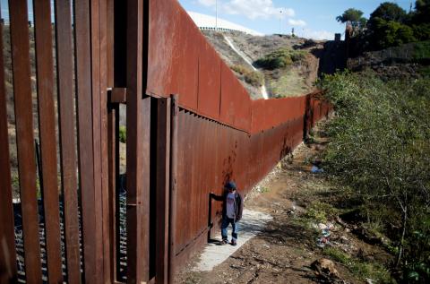 A migrant, part of a caravan of thousands from Central America trying to reach the United States, crosses a flooded area next to the border wall as he tries to cross from Mexico to the U.S., in Tijuana, Mexico, December 7, 2018. PHOTO BY REUTERS/Mohammed Salem