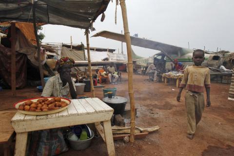 A boy displaced by inter-communal violence in the country walks past a vendor in a camp for displaced persons at Bangui M'Poko International Airport