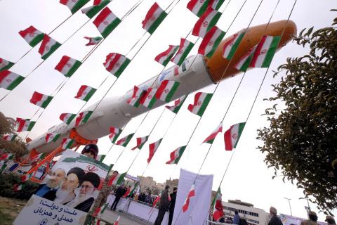 A boy holding a placard with pictures of (L-R) President Hassan Rouhani, the late founder of the Islamic Revolution Ayatollah Ruhollah Khomeini, and Iran's Supreme Leader Ayatollah Ali Khamenei, poses for camera in front of a model of Simorgh satellite-carrier rocket during a ceremony marking the 37th anniversary of the Islamic Revolution, in Tehran February 11, 2016. PHOTO BY REUTERS/Raheb Homavandi