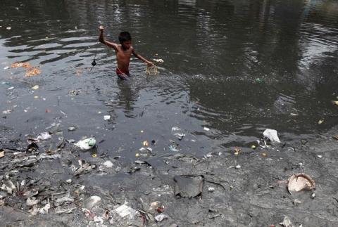 A boy searches for coins thrown by devotees as religious offerings in a polluted water channel near a temple in Kolkata June 5, 2014. Thursday marks this year's World Environment Day. PHOTO BY REUTERS/Rupak De Chowdhuri