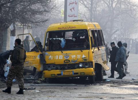 Afghan policemen inspect the wreckage of a bus hit by a suicide attack in Kabul