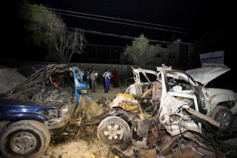 A Somali policemen and journalists gather near the wreckage of vehicles destroyed in a car bomb explosion at the Banadir beach restaurant at Lido beach in Somalia's capital Mogadishu, August 25, 2016. PHOTO BY REUTERS/Feisal Omar