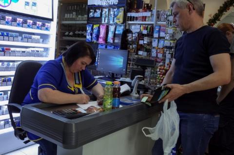 A customer waits while a cashier writes out a purchase receipt for store records, as many business have turned off their digital tills after cases of cyber attacks on business, at a store in Kiev, Ukraine, June 28, 2017. PHOTO BY REUTERS/Gleb Garanich