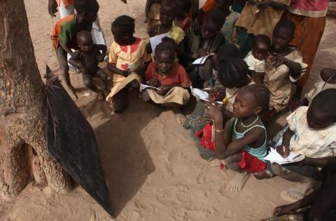 Refugee children copy notes from a chalkboard during an open-air English lesson under a tree at the Yida camp in South Sudan's Unity State