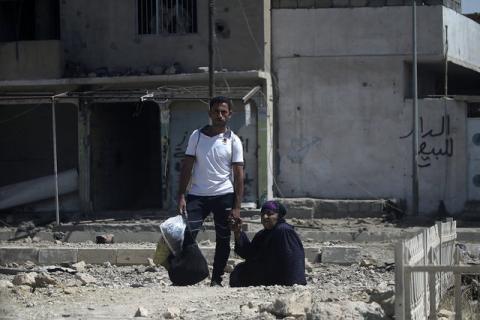 A man holds the hand of an elderly woman as they flee from clashes in western Mosul, Iraq, May 27, 2017. PHOTO BY REUTERS/Alkis Konstantinidis