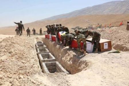 Kurdish peshmerga forces carry coffins, draped with Kurdish flags, containing the remains of Yazidis who were killed by militants of the Islamic State, during a burial ceremony at Mazar Sharaf al-Din, north of Sinjar Mountain, August 13, 2015. PHOTO BY REUTERS/Ari Jalal