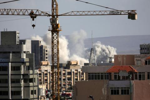 A construction crane is seen as smoke rises from Yarmouk Palestinian camp in Damascus, Syria, April 21, 2018. PHOTO BY REUTERS/Ali Hashisho