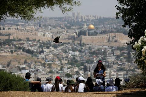 A crow flies past as Jewish school children gather at a look-out point on the Armon Hanatziv Promenade in Jerusalem, May 11, 2017. PHOTO BY REUTERS/Amir Cohen