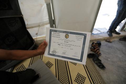 Daman Ayed, a 20-year old former rescue worker with the White Helmets holds a document at a temporary camp in Aleppo countryside, Syria, July 23, 2018. PHOTO BY REUTERS/ Khalil Ashaw