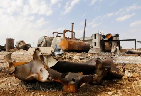 Men walk among debris at an oil refinery and a gas station that were targeted by what activists said were U.S.-led air strikes, in the town of Tel Abyad of Raqqa governorate, near the border with Turkey, October 2, 2014. PHOTO BY REUTERS/Stringer