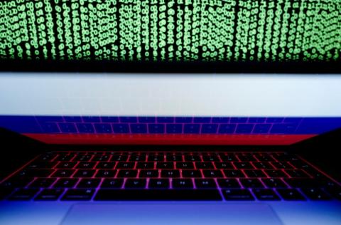 A Russian flag is seen on a laptop screen in front of a computer screen displaying cyber code. REUTERS/Kacper Pempel/Illustration