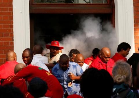 Members of Julius Malema's Economic Freedom Fighters (EFF) flee teargas as they are evicted from Parliament during President Jacob Zuma's question and answer session in Cape Town, South Africa, May 17, 2016. PHOTO BY REUTERS/Mike Hutchings