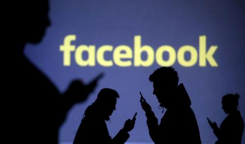 Silhouettes of mobile users are seen next to a screen projection of the Facebook logo in this picture illustration taken March 28, 2018. PHOTO BY REUTERS/Dado Ruvic/Illustration