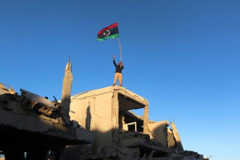 A fighter of Libyan forces allied with the U.N.-backed government waving a Libyan flag flashes victory sign as he stands atop the ruins of a house after forces finished clearing Ghiza Bahriya, the final district of the former Islamic State stronghold of Sirte, Libya. PHOTO BY REUTERS/Hani Amara
