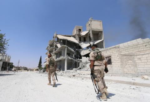 Syria Democratic Forces (SDF) fighters walk near rising smoke and damaged buildings on a street in Manbij, in Aleppo Governorate, Syria, August 7, 2016. PHOTO BY REUTERS/Rodi Said