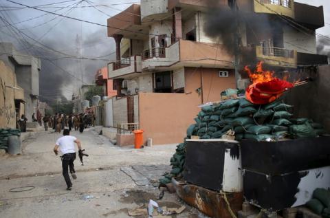 A Kurdish gunman runs across a street in Tuz Khurmato during clashes between Shi'ite militia and Kurdish gunmen, Iraq. PHOTO BY REUTERS/Goran Tomasevic