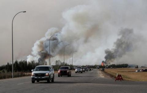 A group of evacuees in a convoy drive in front of smoke from the the wildfires near Fort McMurray, Alberta, Canada, May 6, 2016. PHOTO BY REUTERS/Mark Blinch