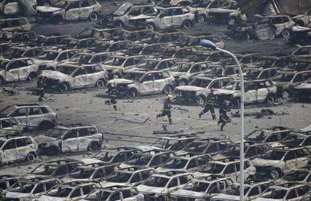 Firefighters run as smoke rises at the site of the explosions at the Binhai new district in Tianjin, China, August 14, 2015. PHOTO BY REUTERS/Jason Lee