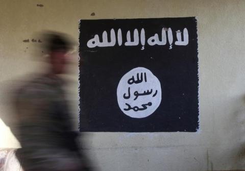 A member of the Iraqi rapid response forces walks past a wall painted with the black flag commonly used by Islamic State militants, at a hospital damaged by clashes during a battle between Iraqi forces and Islamic State militants in the Wahda district of eastern Mosul, Iraq, January 8, 2017. PHOTO BY REUTERS/Alaa Al-Marjani