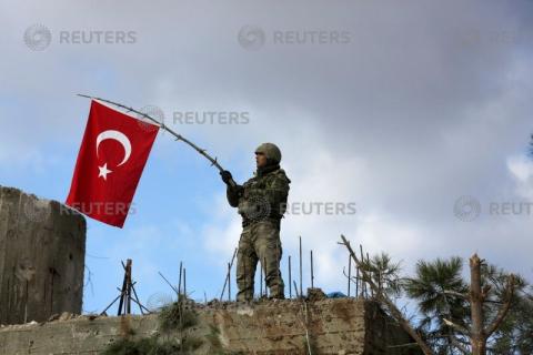 A Turkish soldier waves a flag on Mount Barsaya, northeast of Afrin, Syria, January 28, 2018. PHOTO BY REUTERS/ Khalil Ashawi