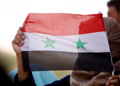 A woman holds a Syrian flag in Deraa, Syria, July 4, 2018. REUTERS/Omar Sanadiki/