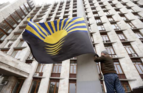 A man raises the Donetsk flag at the regional administration building in the eastern city of Donetsk