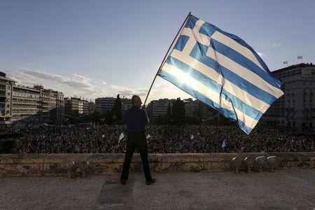 A man waves a Greek national flag while standing at the premises of the parliament building during a rally in front of the parliament building calling on the government to clinch a deal with its international creditors and secure Greece's future in the Eurozone, in Athens, Greece, June 22, 2015. PHOTO BY REUTERS/Yiannis Liakos/Intimenews