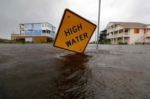 Flood waters lap at a high water warning sign that was partially pushed over by Hurricane Florence on Oak Island, North Carolina, U.S., September 15, 2018. PHOTO BY REUTERS/Jonathan Drake