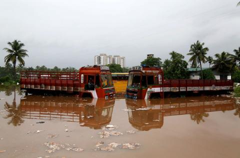 Partially submerged trucks are seen surrounded by floodwaters at a parking bay after the opening of Idamalayr, Cheruthoni and Mullaperiyar dam shutters following heavy rains, on the outskirts of Kochi, August 16, 2018. PHOTO BY REUTERS/Sivaram V
