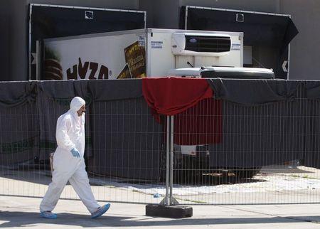 A member of a forensic team walks in front of a truck in which more than 70 bodies were found, at a customs building with refrigeration facilities in the village of Nickelsdorf, Austria, August 29, 2015. PHOTO BY REUTERS/Heinz-Peter Bader