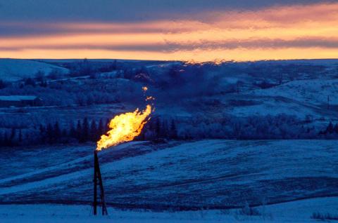 A natural gas flare on an oil well pad burns as the sun sets outside Watford City, North Dakota, January 21, 2016. PHOTO BY REUTERS/Andrew Cullen