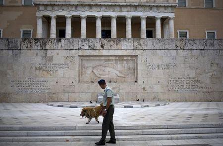 A member of the Greek Presidential guard walks next to a stray dog in front of the parliament building in Athens, Greece, August 22, 2015. PHOTO BY REUTERS/Stoyan Nenov