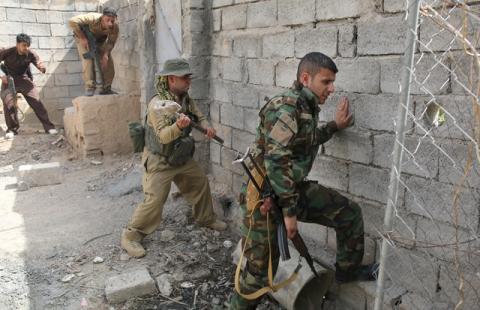 A Kurdish gunman uses a hammer to open a hole in a wall near Shi'ite militiamen positions during clashes Tuz Khurmato, Iraq, April 24, 2016. PHOTO BY REUTERS/Goran Tomasevic