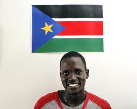Guor Marial, 28, smiles in his apartment under a South Sudan flag in Flagstaff, Arizona July 21, 2012. PHOTO BY REUTERS/Darryl Webb