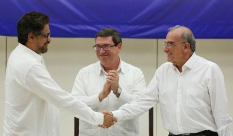 Colombia's FARC lead negotiator Ivan Marquez (L) and Colombia's lead government negotiator Humberto de la Calle (R) shake hands while Cuba's Foreign Minister Bruno Rodriguez looks on, after signing a final peace deal in Havana, Cuba, August 24, 2016. PHOTO BY REUTERS/Alexandre Meneghini