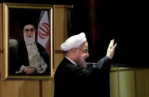 Iranian President Hassan Rouhani waves as he stands next to a portrait of Iran's Supreme Leader Ayatollah Ali Khamenei, after he registered for February's election of the Assembly of Experts, the clerical body that chooses the supreme leader, at Interior Ministry in Tehran, December 21, 2015. PHOTO BY REUTERS/Raheb Homavandi
