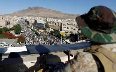 A Houthi militant sits guard on the roof of a building overlooking fellow Houthis rallying to denounce the rapid devaluation of the Yemeni Rial in Sanaa, Yemen, October 5, 2018. PHOTO BY REUTERS/Khaled Abdullah