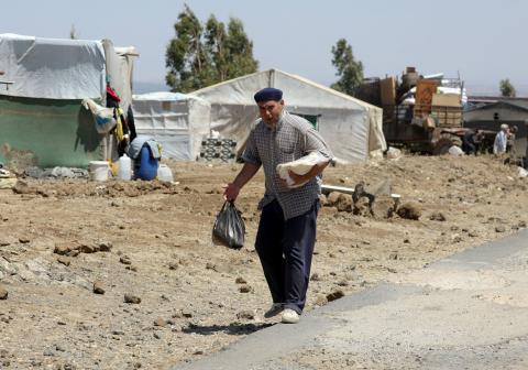 Internally displaced man holds a stack of bread near the Israeli-occupied Golan Heights in Quneitra, Syria July 11, 2018. PHOTO BY REUTERS/Alaa Al-Faqir