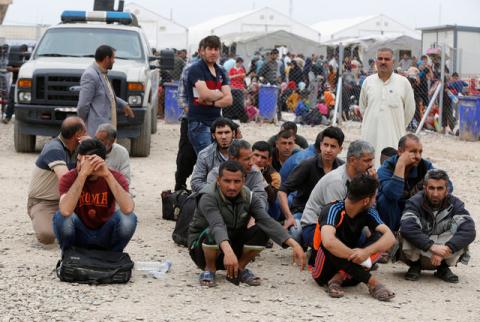 Displaced Iraqi men who fled their homes during a battle between Iraqi forces and Islamic State militants, wait for a security check at Hammam al-Alil camp checkpoint south of Mosul, Iraq, April 18, 2017. PHOTO BY REUTERS/Muhammad Hamed