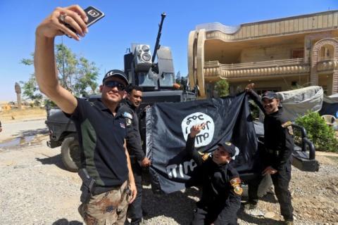 Members of the Iraqi Army are photographed with an Islamic State flag, claimed after fighting with Islamic State militants in western Mosul, Iraq, June 26, 2017. PHOTO BY REUTERS/Alaa Al-Marjani