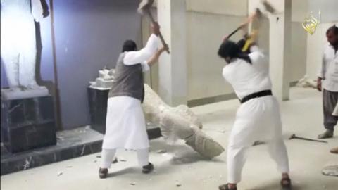 Men use sledgehammers on a toppled statue in a museum at a location said to be Mosul in this still image taken from an undated video. PHOTO BY REUTERS/Social media Web site via Reuters TV