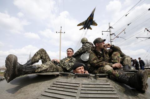 A fighter jet flies above as Ukrainian soldiers sit on an armoured personnel carrier in Kramatorsk, in eastern Ukraine, April 16, 2014. PHOTO BY REUTERS/Marko Djurica
